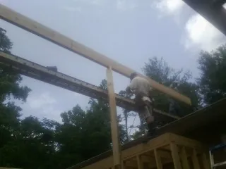 Carpenter setting a ridge beam over a new addition frame — Ice Dam Removal by Roofing Brothers in Livonia