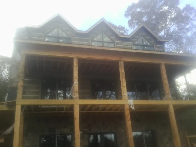 Dormers and porch framing on a large log home under construction — Roof Coating work by our crew in Livonia