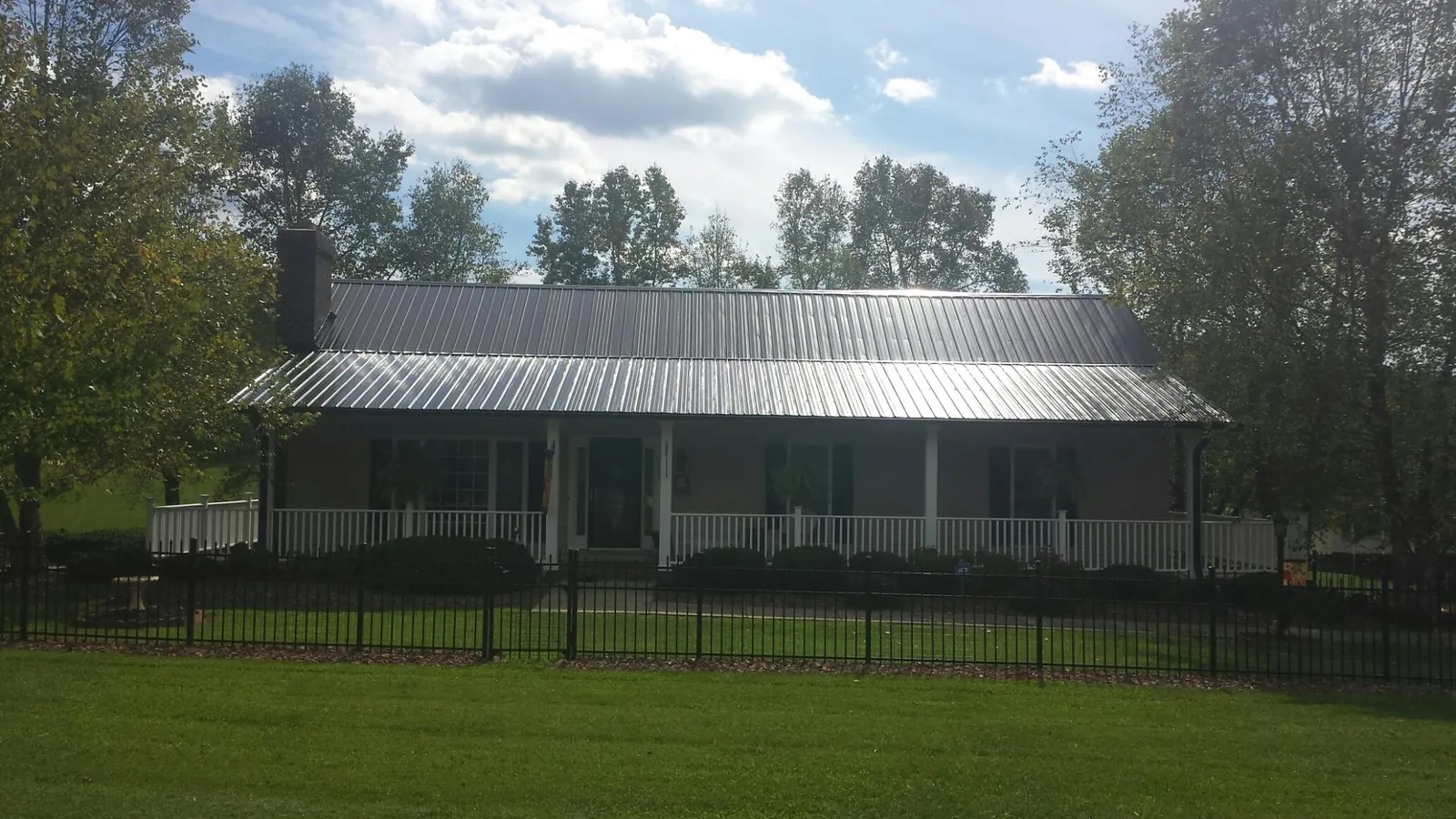 Gray metal roof on a brick ranch with a full width front porch — Gutter Guard Installation work by our crew in Livonia