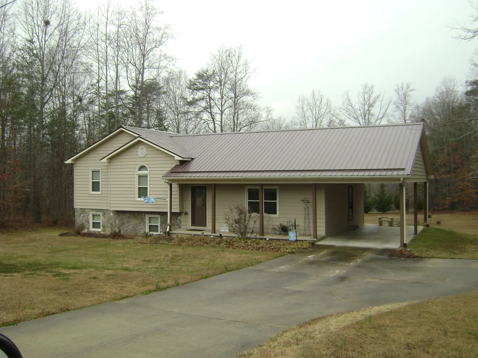 Brown metal roof on a tan split level home with an attached carport in Livonia